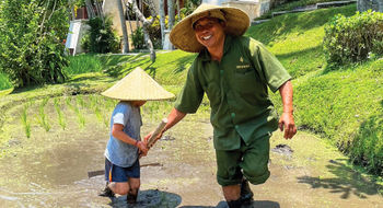 Travel Weekly editor Christina Jelski's son planting rice seedlings with Wirawan, an agricultural expert at the Four Seasons Resort Bali at Sayan.
